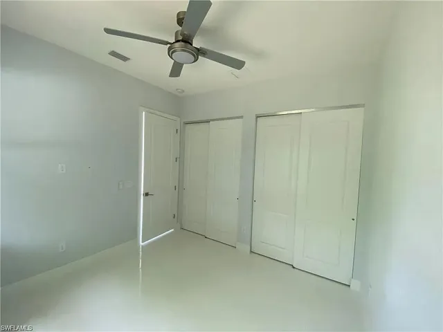 Unfurnished bedroom featuring two closets and a ceiling fan