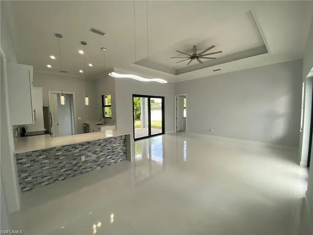 Kitchen featuring white cabinetry, decorative light fixtures, a ceiling fan, light tile patterned flooring, and a raised ceiling