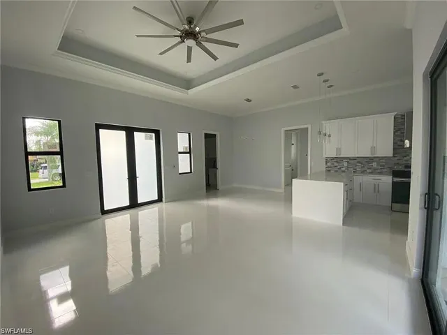 Unfurnished living room with french doors, ceiling fan, and ornamental molding