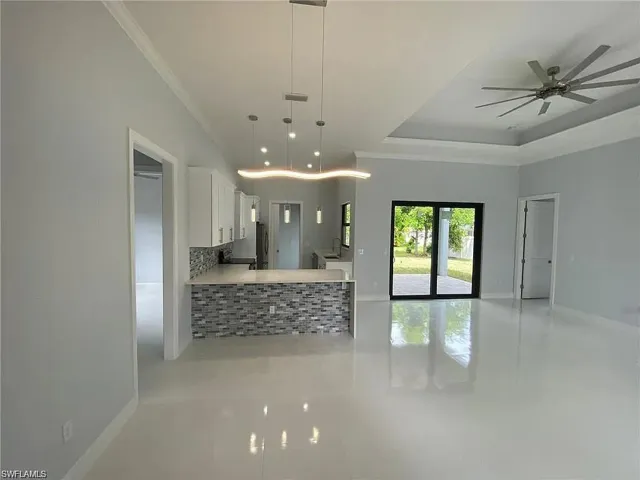 Kitchen featuring white cabinets, open floor plan, backsplash, decorative light fixtures, and light tile patterned flooring