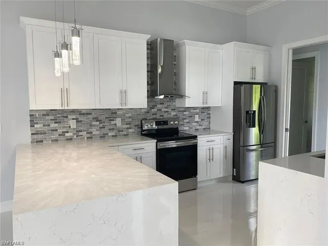 Kitchen with stainless steel appliances, light stone counters, white cabinets, pendant lighting, and ornamental molding