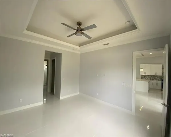 Empty room featuring crown molding, a ceiling fan, and a tray ceiling