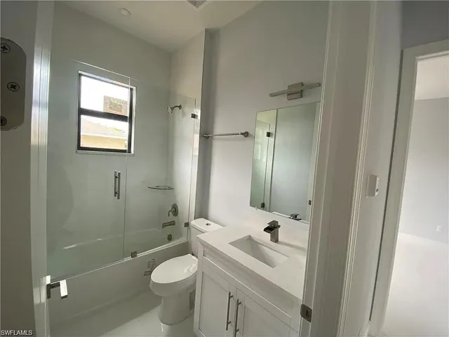 Full bathroom featuring vanity and bath / shower combo with glass door