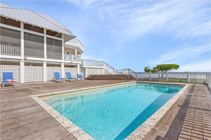 View of pool featuring a wooden deck, a sunroom, stairs, and a patio