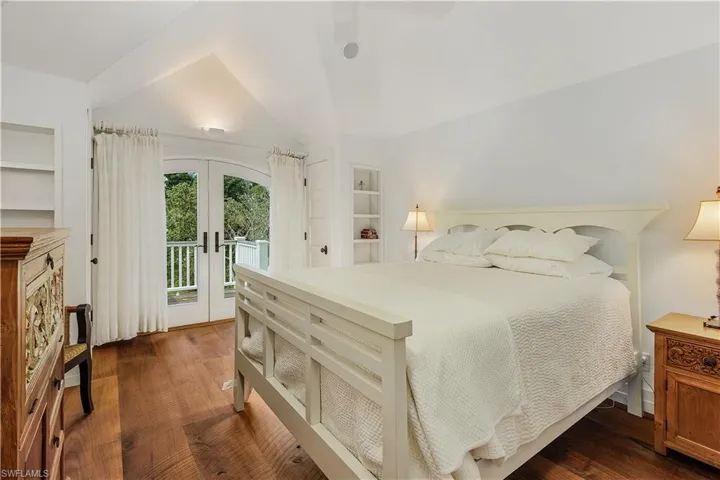Bedroom featuring french doors, dark wood-style floors, access to outside, a ceiling fan, and vaulted ceiling