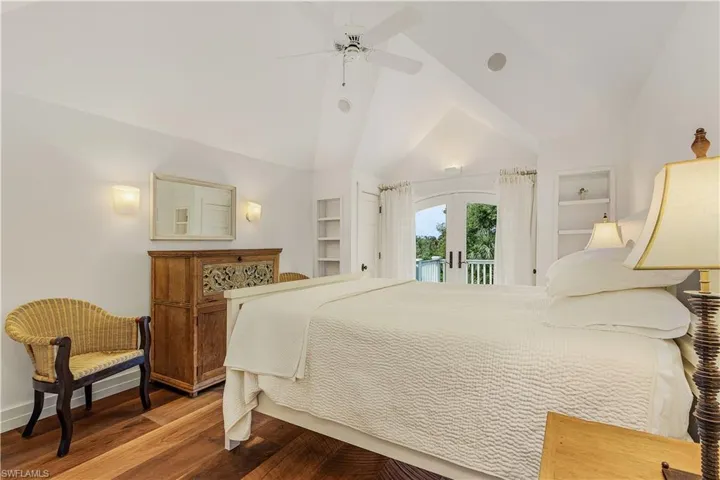 Bedroom with french doors, wood finished floors, access to outside, vaulted ceiling, and ceiling fan