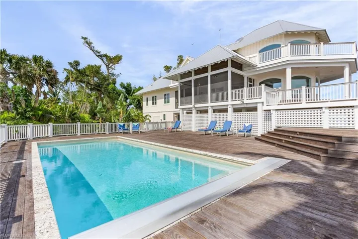 View of swimming pool with a wooden deck, a fenced backyard, a sunroom, and a patio