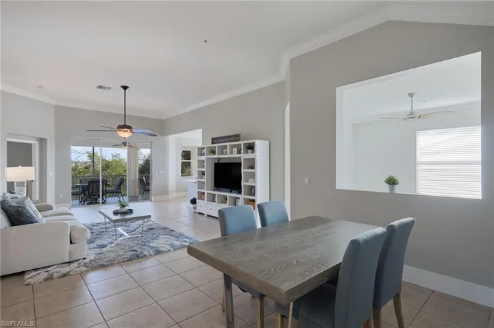 Dining area featuring ceiling fan, light tile patterned floors, and crown molding