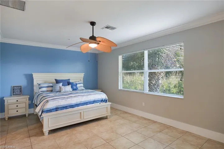 Tiled bedroom featuring crown molding and ceiling fan