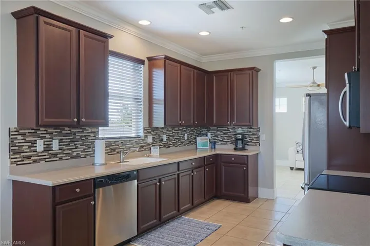 Kitchen with appliances with stainless steel finishes, dark brown cabinetry, healthy amount of natural light, ornamental molding, and recessed lighting