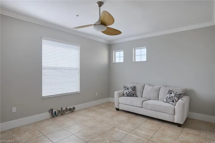 Sitting room featuring crown molding, a ceiling fan, and light tile patterned floors