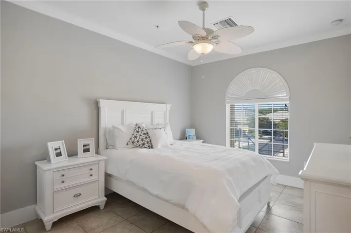 Bedroom with ornamental molding, a ceiling fan, and light tile patterned flooring