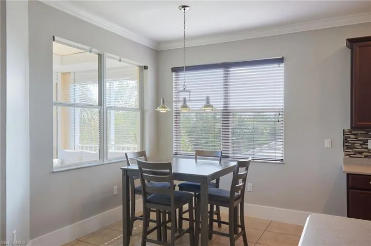 Dining area featuring light tile patterned floors and crown molding