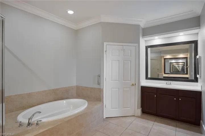 Full bath featuring vanity, ornamental molding, light tile patterned floors, recessed lighting, and a garden tub