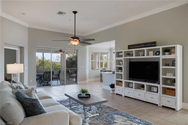 Living room featuring light tile patterned flooring, ornamental molding, and ceiling fan