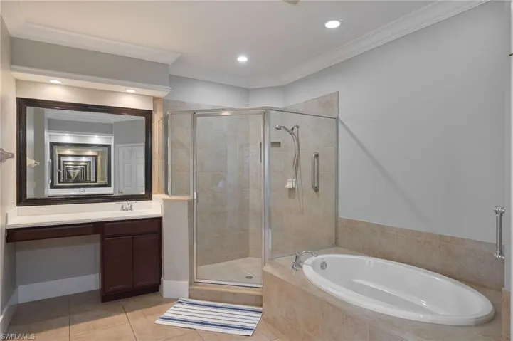 Full bathroom with ornamental molding, a garden tub, light tile patterned flooring, a shower stall, and vanity