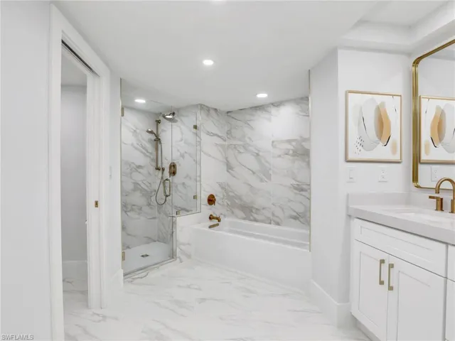 Bathroom with a marble finish shower, a tub to relax in, baseboards, recessed lighting, and vanity