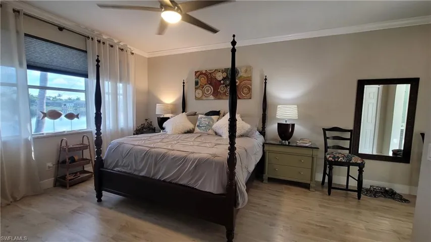 Bedroom featuring ceiling fan, hardwood / wood-style flooring, and crown molding