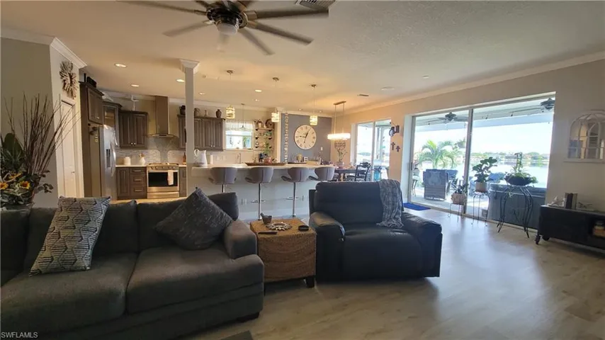 Living room featuring crown molding, ceiling fan, a textured ceiling, and hardwood / wood-style floors