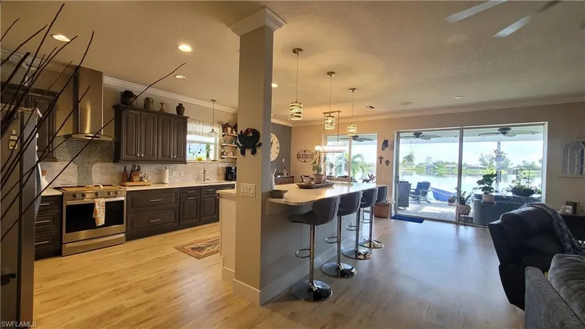 Kitchen featuring a healthy amount of sunlight, light wood-type flooring, tasteful backsplash, and stainless steel stove