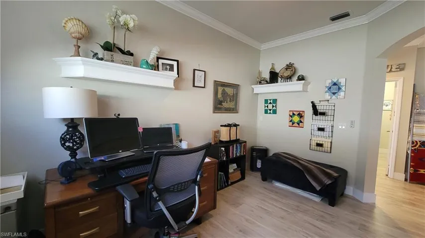 Office area featuring wood-type flooring and crown molding