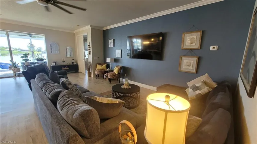 Living room featuring hardwood / wood-style floors, ornamental molding, and ceiling fan