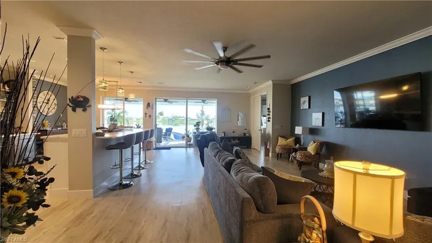 Living room featuring crown molding, wood-type flooring, and ceiling fan