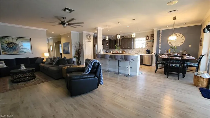 Living room featuring ceiling fan, ornamental molding, and light wood-type flooring