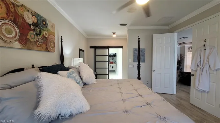 Bedroom featuring a barn door, crown molding, and wood-type flooring