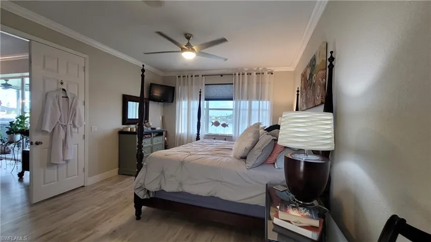 Bedroom with crown molding, wood-type flooring, and ceiling fan