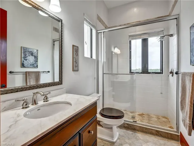 Bathroom featuring a rich wood-tone vanity with a marble-finish countertop, undermount sink, and brushed nickel fixtures