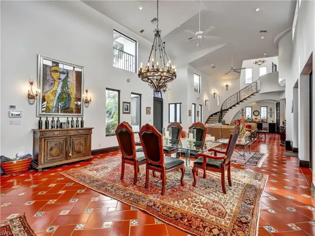 Dining area with high ceilings featuring a grand chandelier and terracotta tile flooring