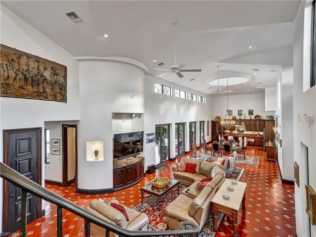 Expansive living area with high ceilings, recessed lighting, and patterned terra cotta flooring
