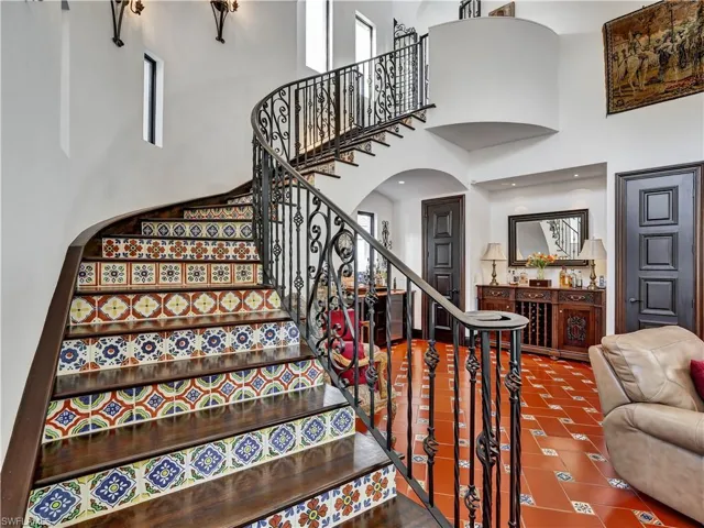 Sweeping staircase featuring decorative risers and wrought iron balusters