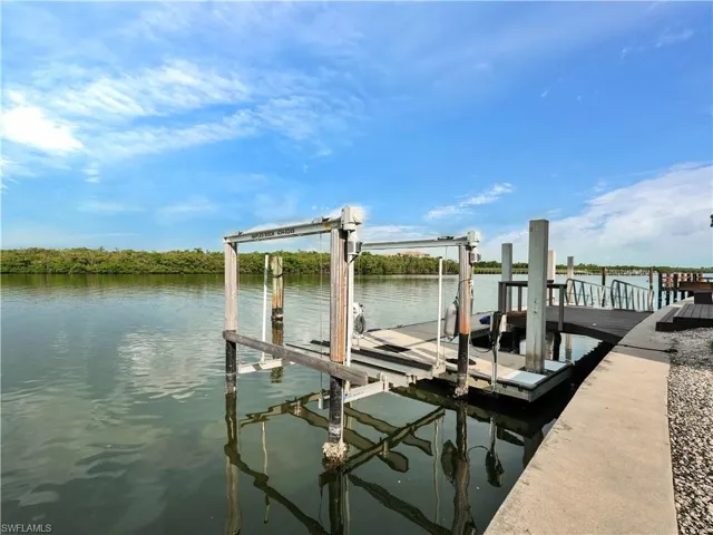 Waterfront dock with a boat lift, composite decking, and concrete seawall