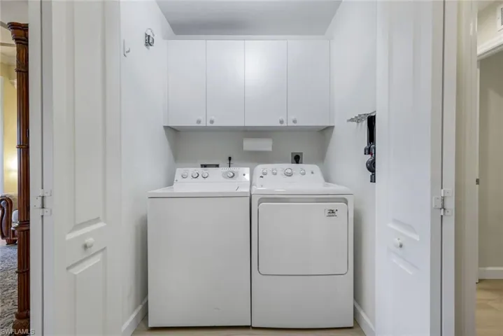 Laundry area featuring baseboards, cabinet space, light wood-type flooring, and washer and dryer