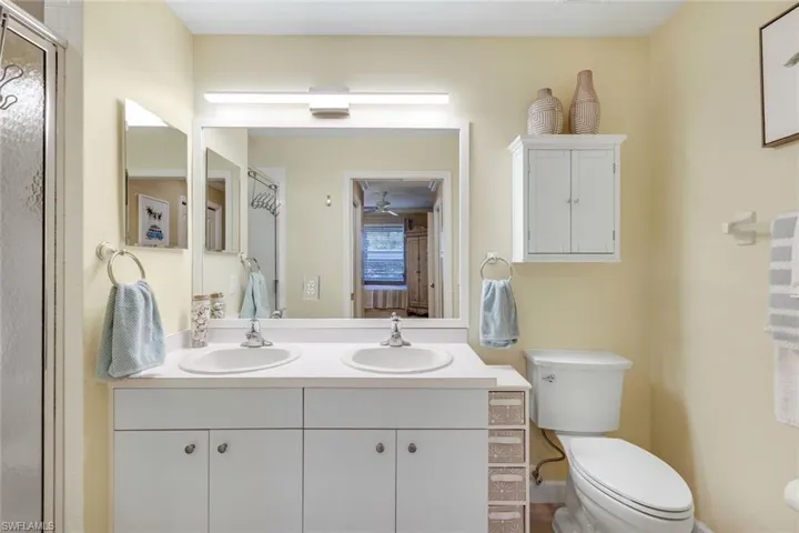 Bathroom featuring toilet, a sink, double vanity, and a shower stall