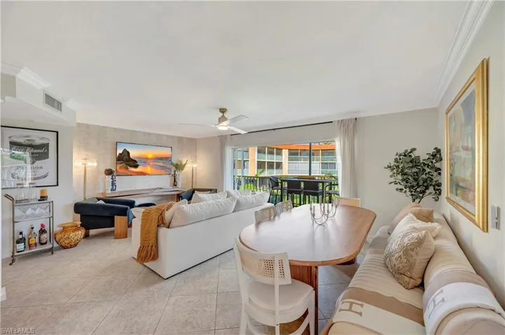 Great room with living and dining area with ornamental molding, light tile patterned floors, and ceiling fan