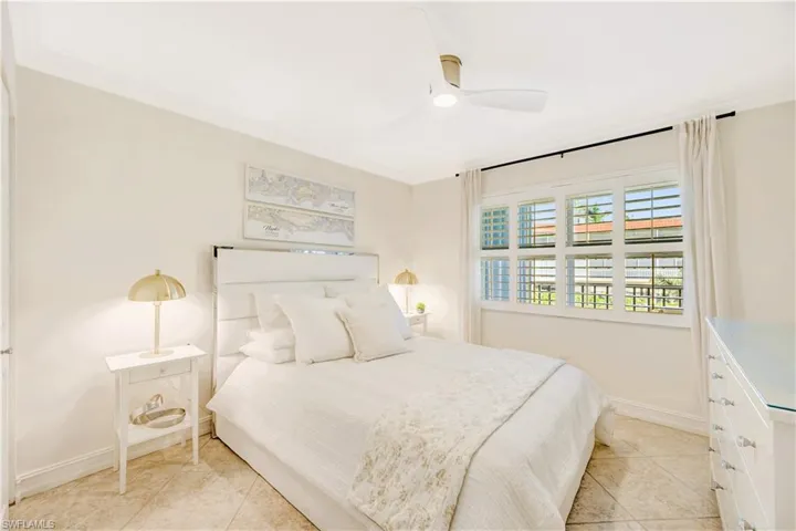 Guest bedroom featuring queen-size bed, crown molding, ceiling fan, and light tile floors