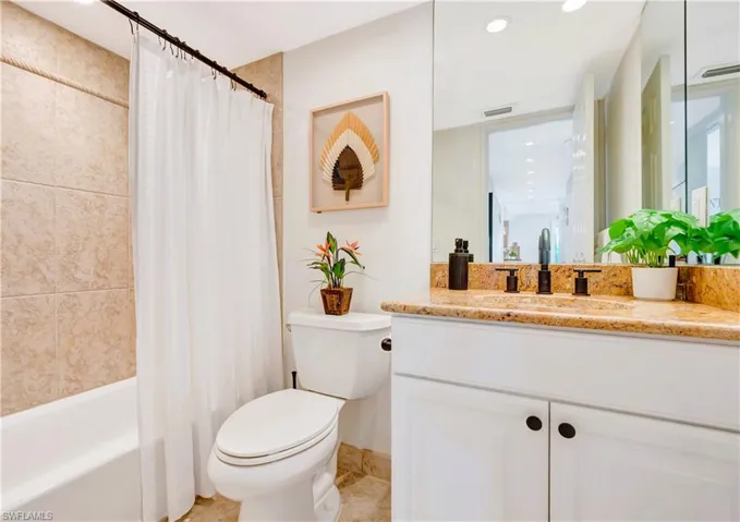 Full guest bathroom with vanity, toilet, tile flooring, and shower / bath combo