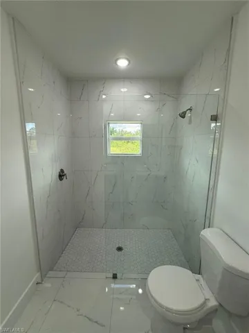 Bathroom with a marble finish shower and marble look tiles