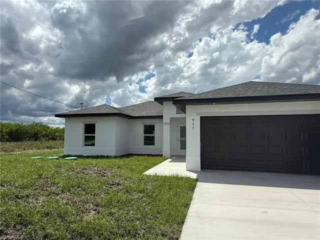 Prairie-style home with concrete driveway, stucco siding, a garage, roof with shingles, and a front lawn