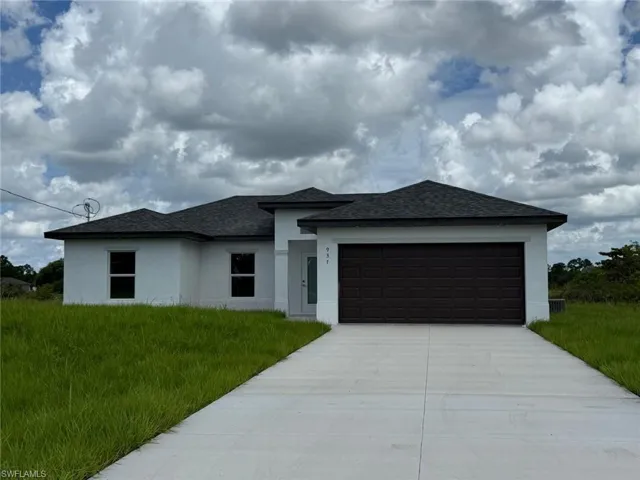 Prairie-style house with stucco siding, roof with shingles, an attached garage, and driveway