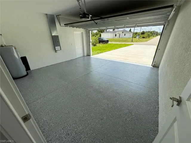 Garage with a textured wall, water heater, electric panel, and a garage door opener