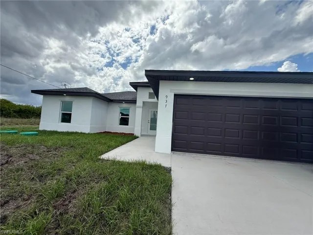View of front of house featuring stucco siding, driveway, and a garage