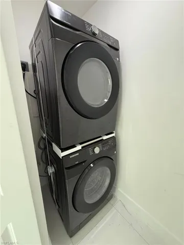 Laundry area featuring stacked washing machine and dryer and baseboards