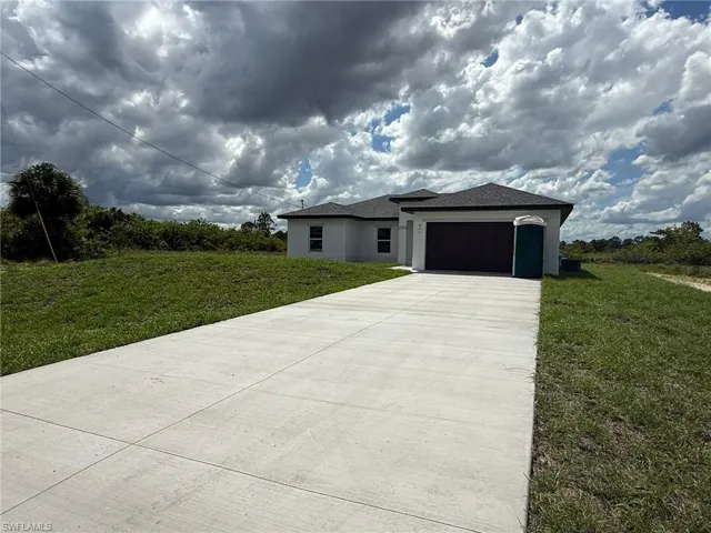 Prairie-style house featuring a front lawn, concrete driveway, a garage, and stucco siding