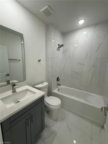 Full bathroom with shower / washtub combination, vanity, light marble finish flooring, and recessed lighting