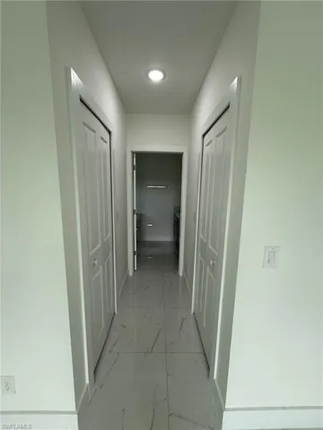 Hallway with light marble finish flooring and baseboards