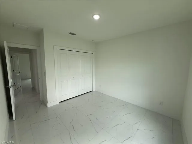 Unfurnished bedroom with light marble finish flooring, a closet, and recessed lighting